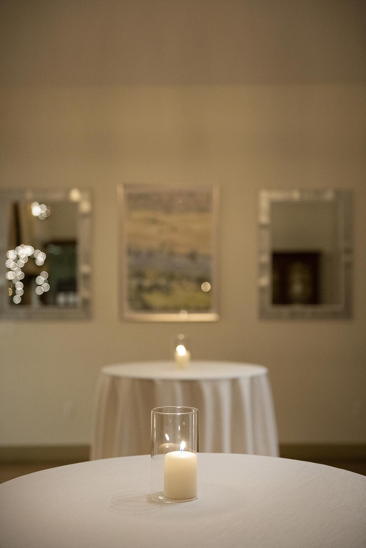Two round tables with candles in a softly lit room.