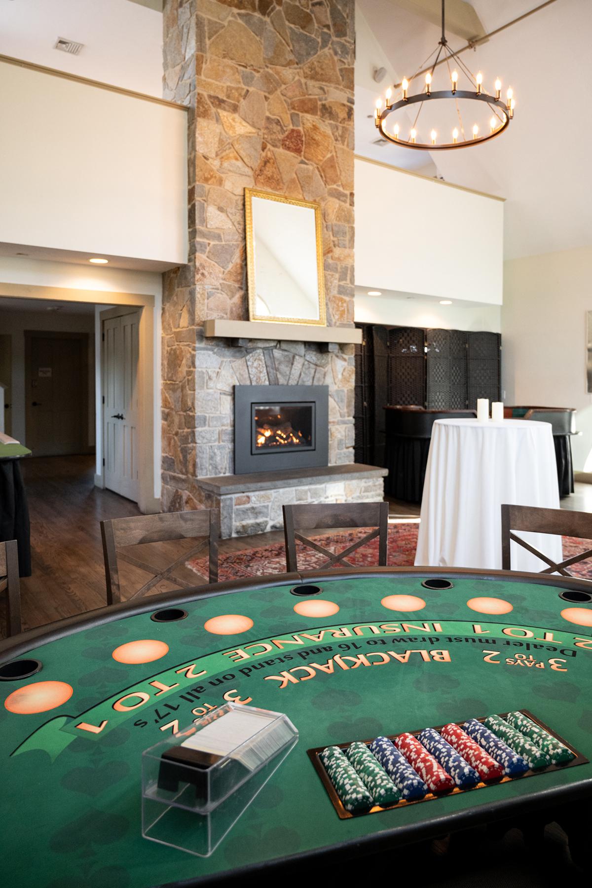 Cozy room with a fireplace, round chandelier, and blackjack table.