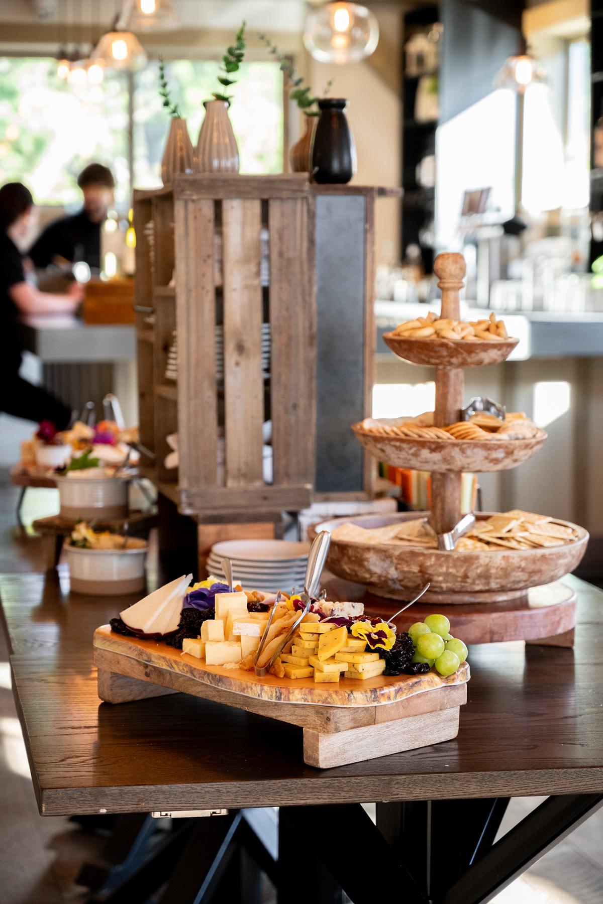 Cheese and fruit platters on a wooden table in a bright room.