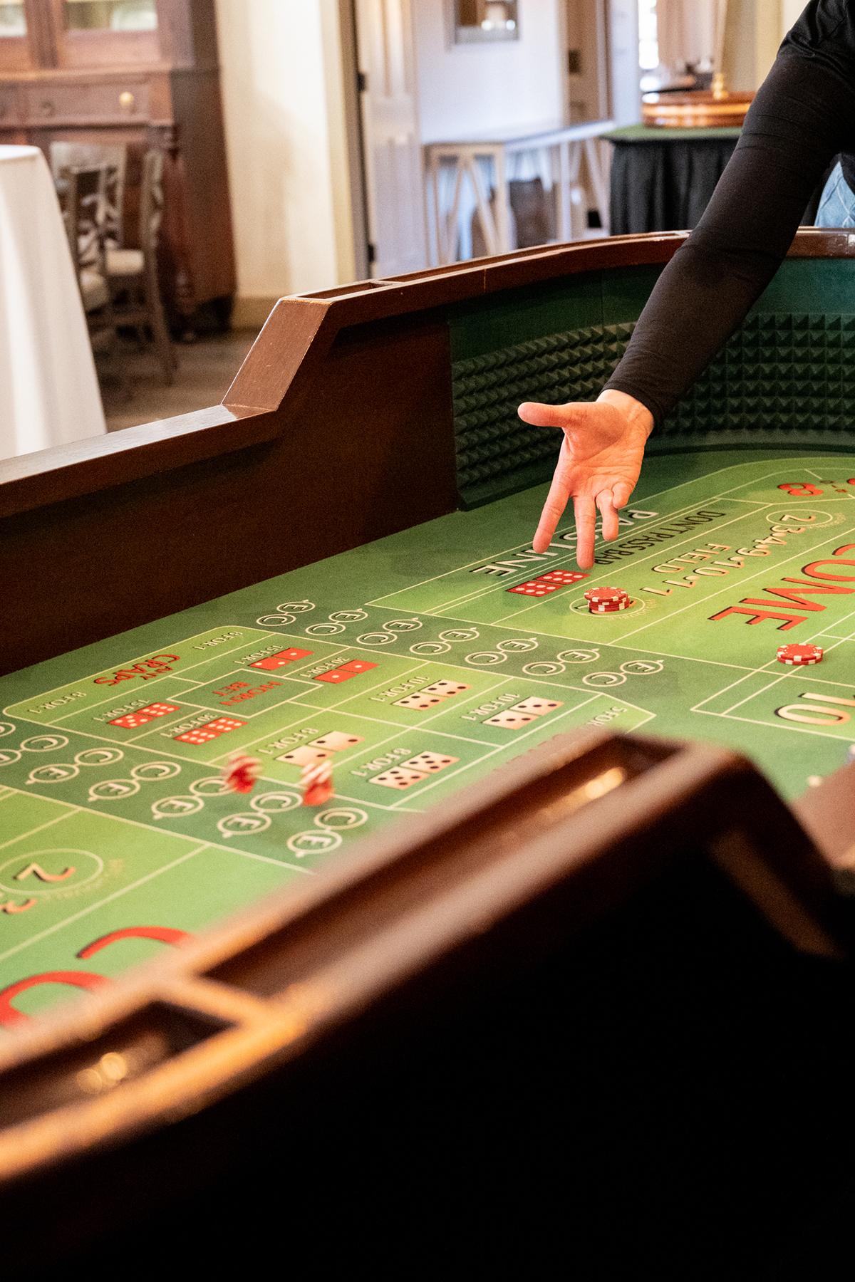 Casino craps table with a person's hand reaching over it.