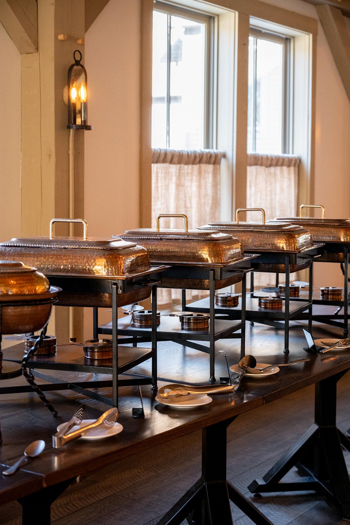 Buffet setup with chafing dishes on a wooden table.