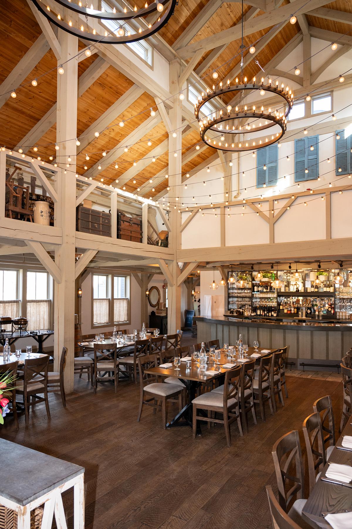 Rustic restaurant interior with wooden beams and chandeliers.