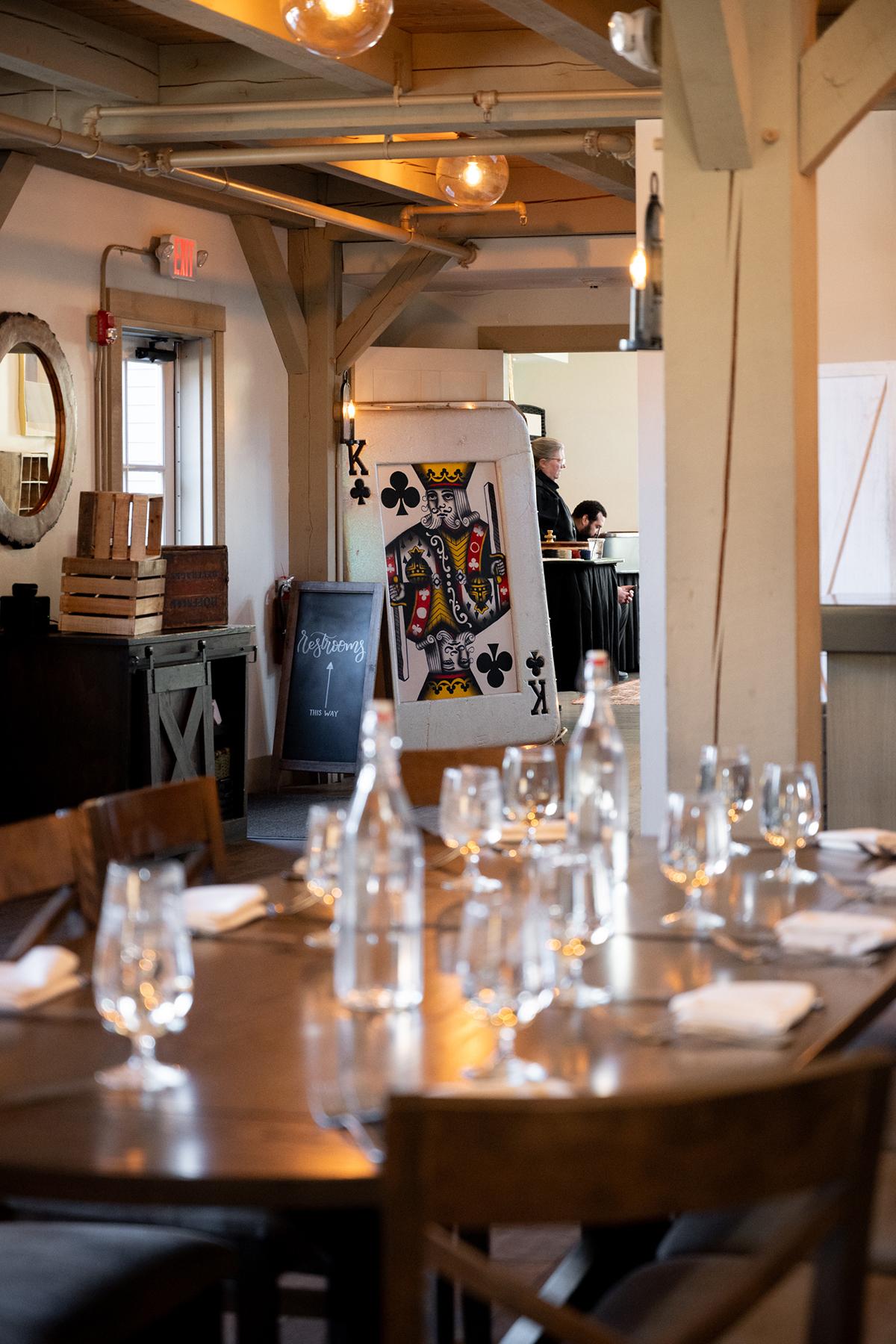 Rustic restaurant with a large table set for dining; dim lighting, playing card decor.