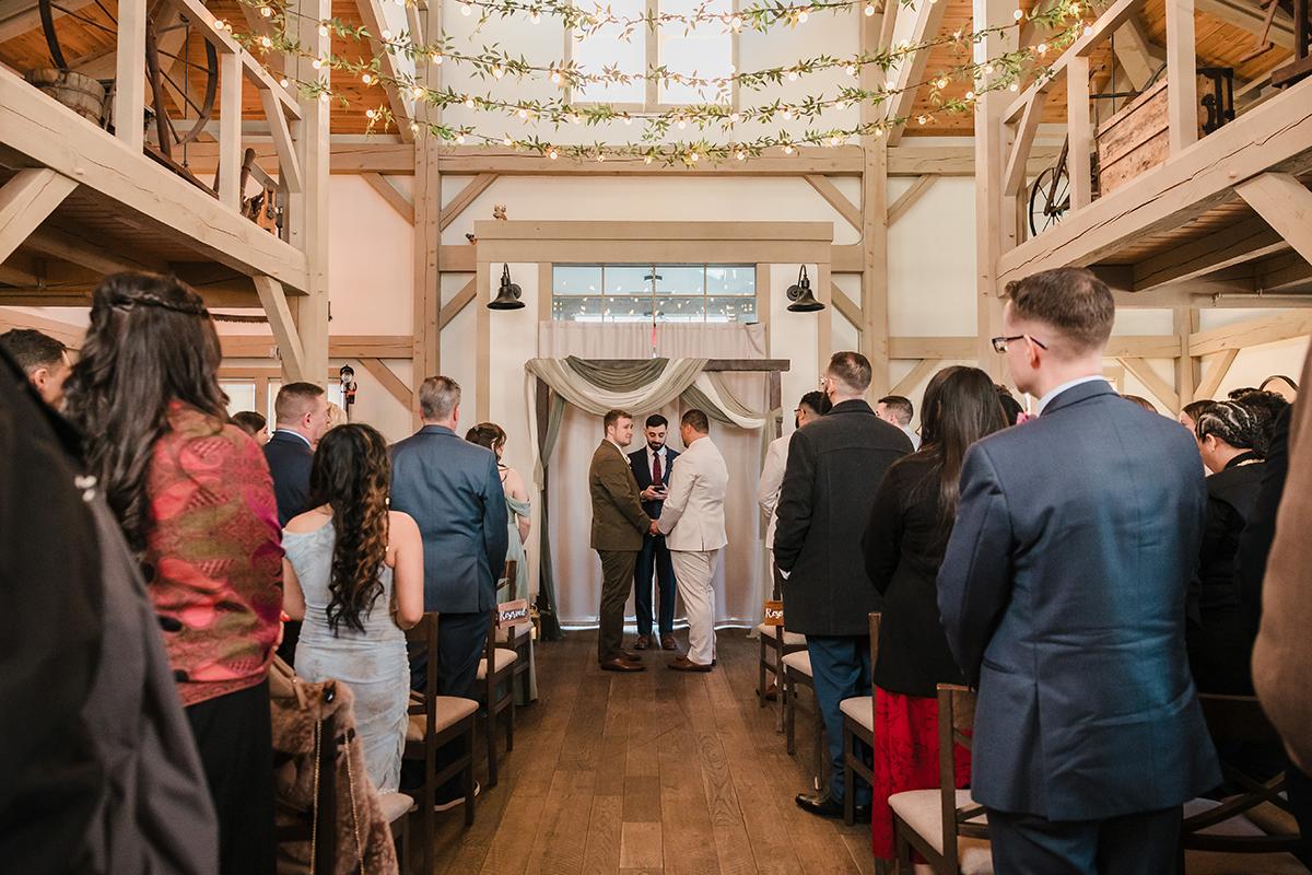 Wedding ceremony in a rustic venue with guests seated and two people at the altar.