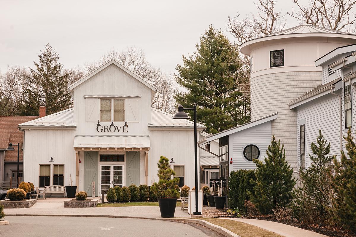 White building with Crowne sign, surrounded by trees and shrubs, overcast sky.