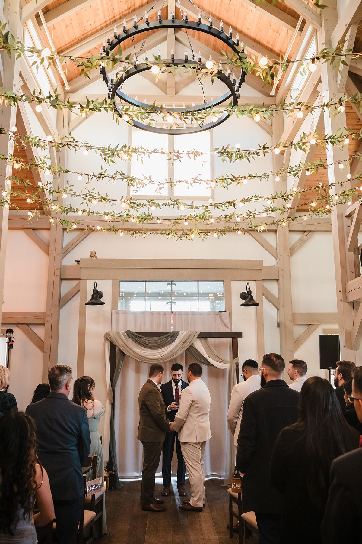 Indoor wedding ceremony with high ceiling and guests seated.