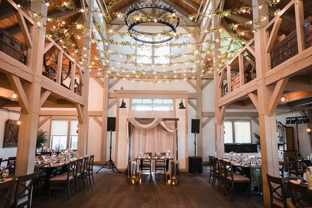 Bright, rustic wedding venue with string lights and wooden beams.