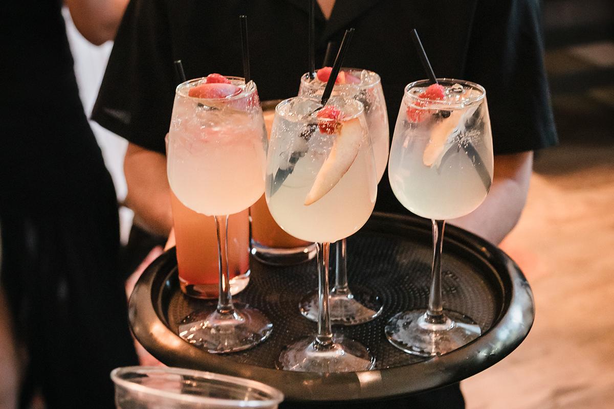 Four cocktails with fruit garnishes on a tray.