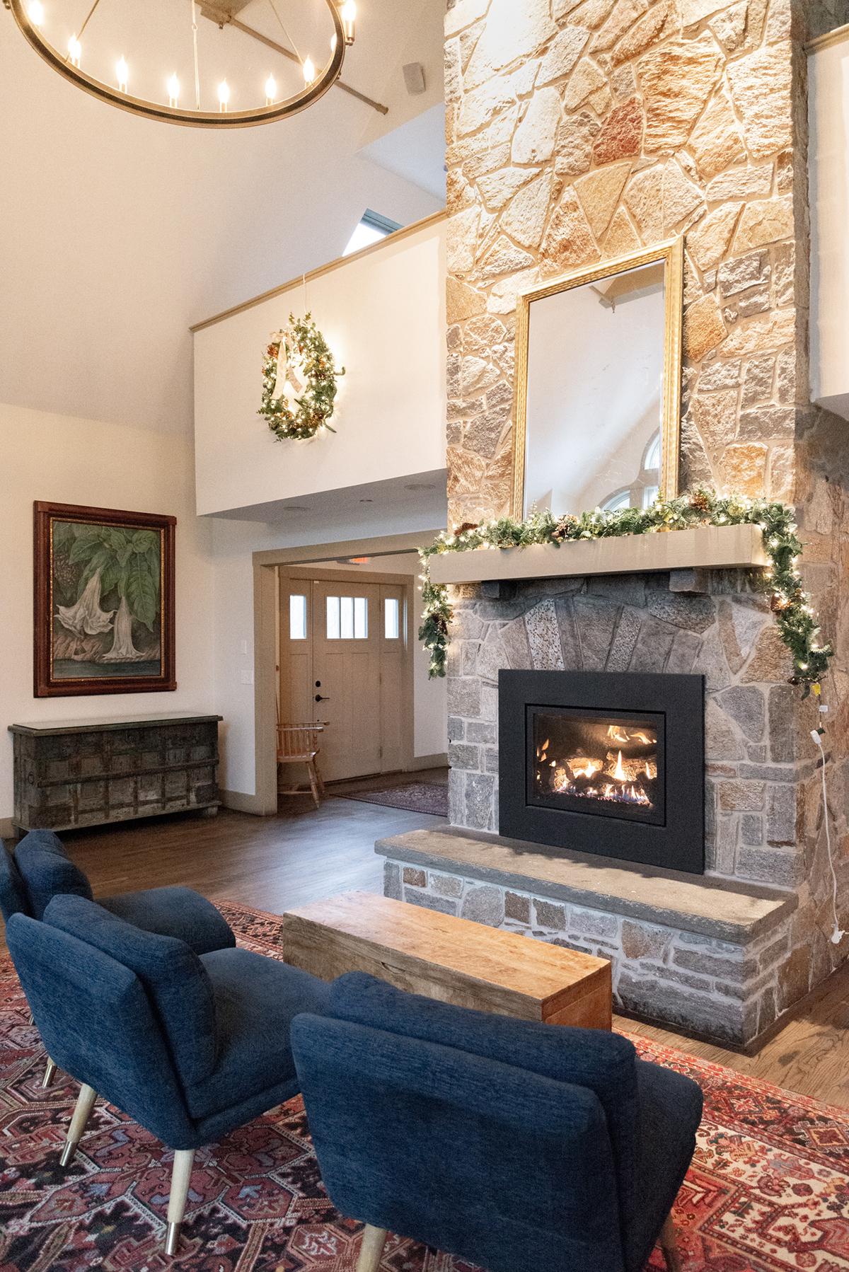 Cozy living room with blue chairs, stone fireplace, and tall vaulted ceiling