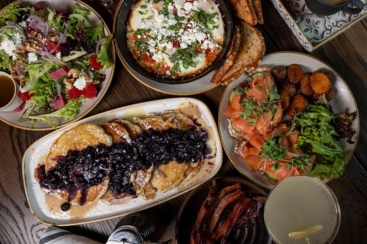 Overhead view of a table with roasted meats, salad, rice, and assorted dishes.