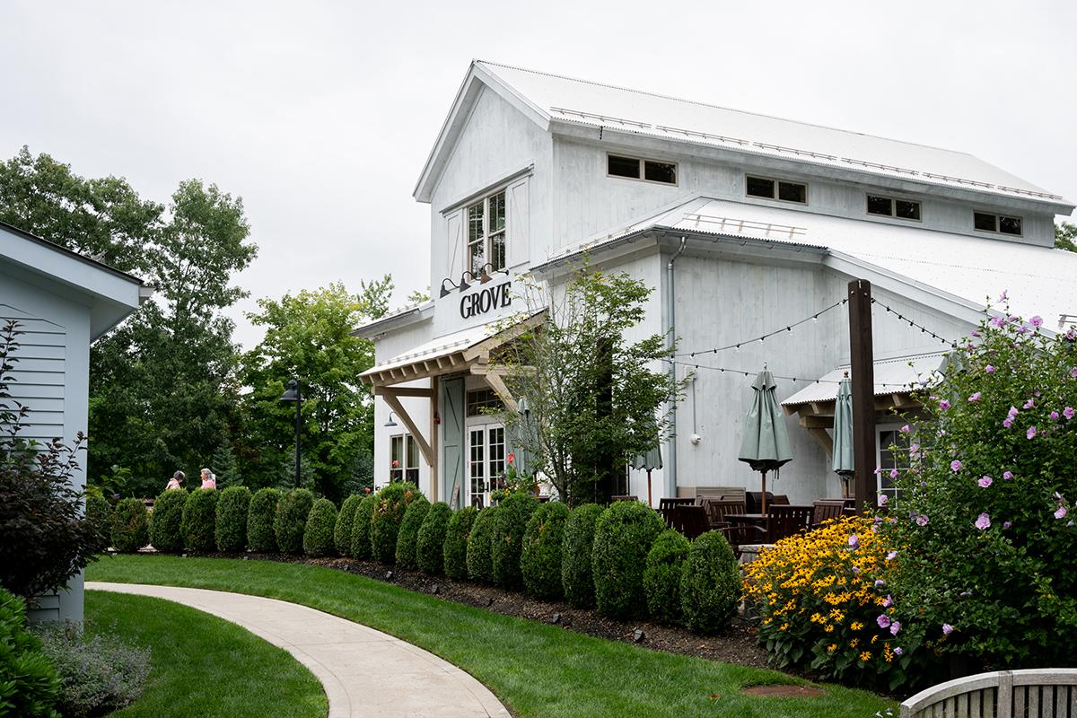 White two-story house with lush garden and curved walkway.