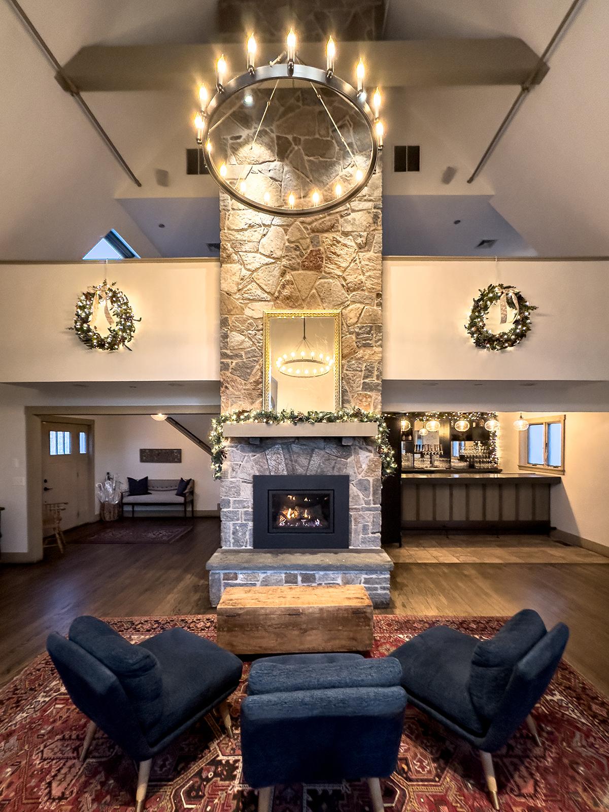 Cozy living room with stone fireplace, chandelier, and dark blue chairs.