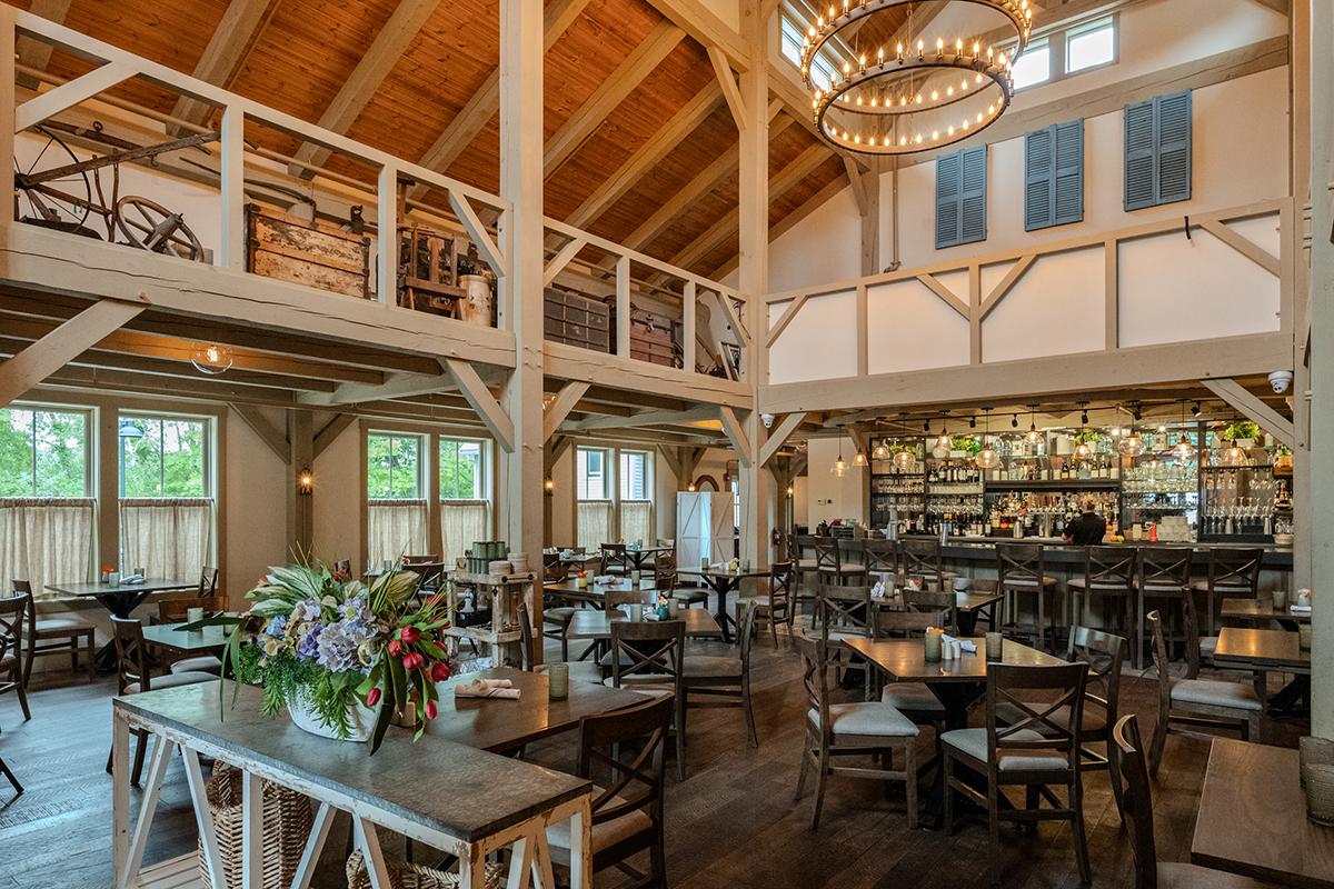 Rustic restaurant interior with wooden beams, chandelier, and tables.
