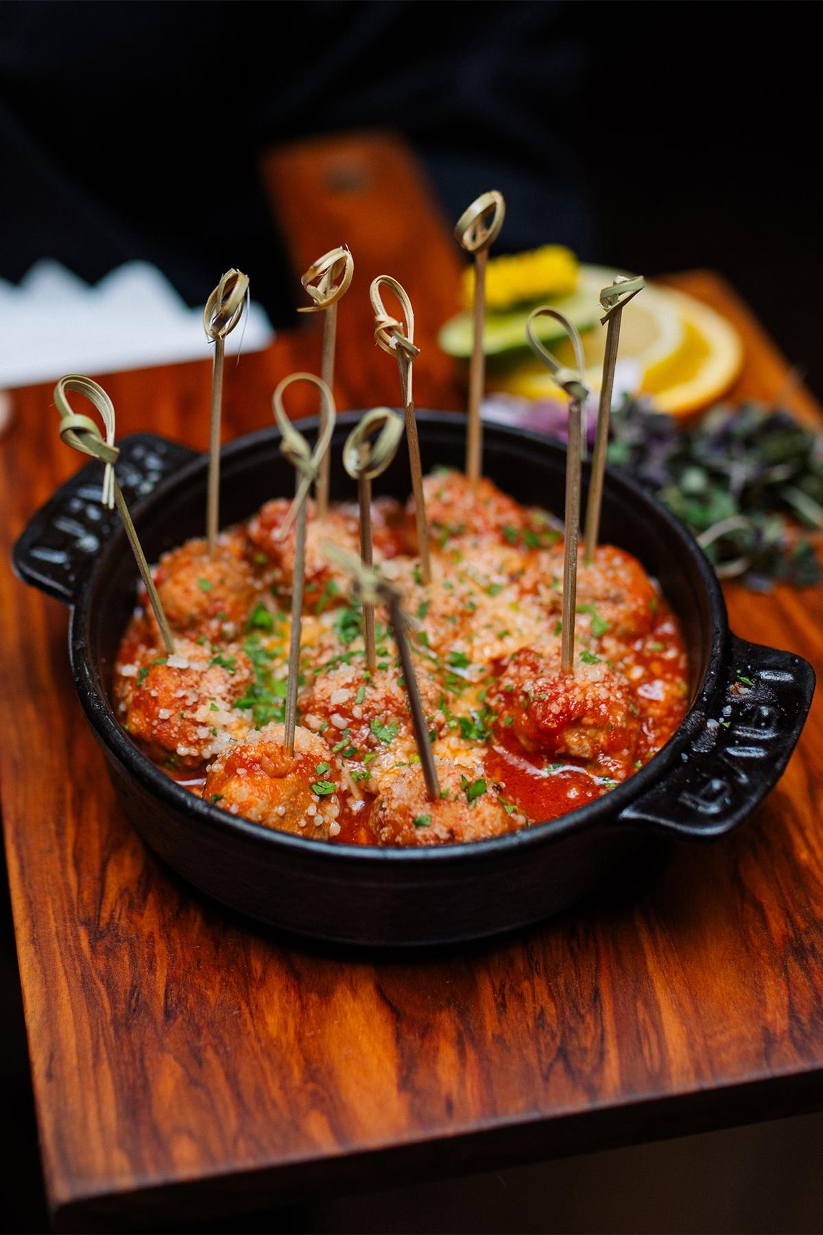 Skillet of tomato sauce topped with herbs and cheese, served with breadsticks