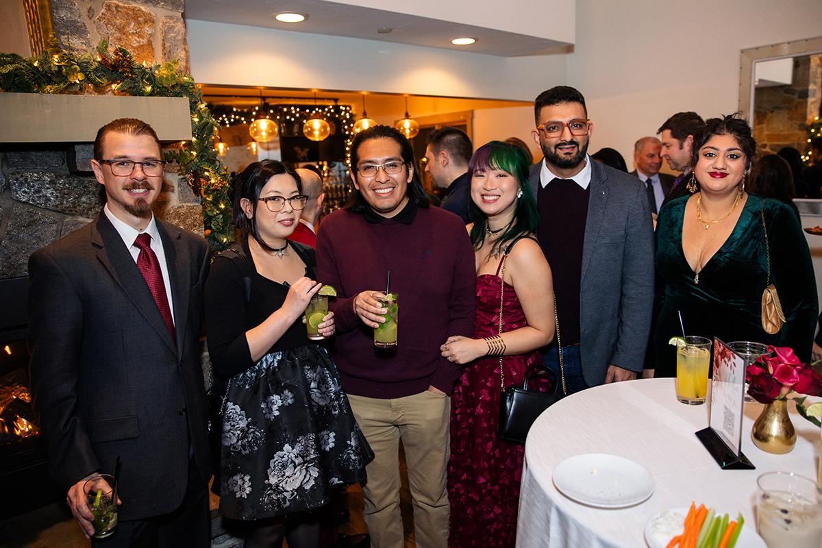 Group of elegantly dressed guests posing at a reception table with drinks.