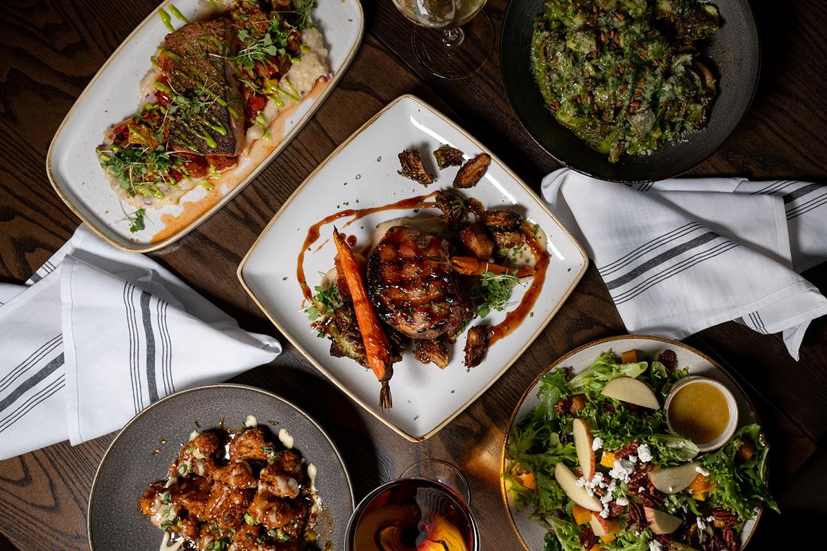 Overhead photo of Thai dishes, including grilled fish, prawns, curry, and salad.